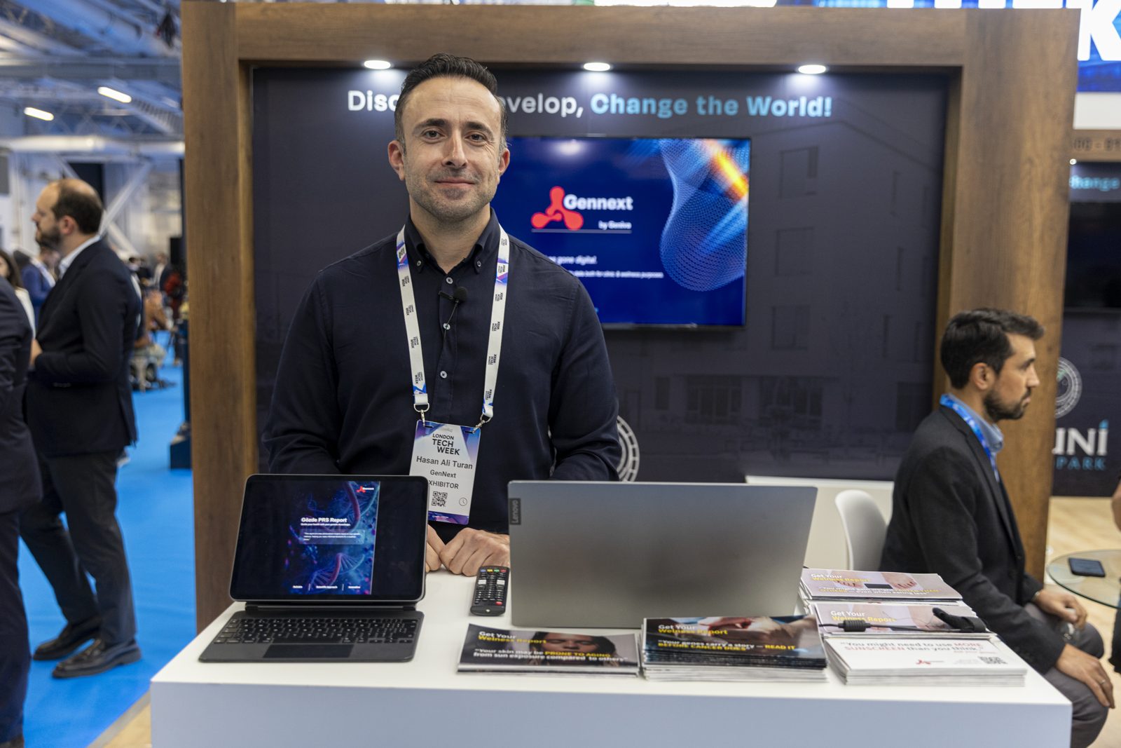 Presenter at a screen-equipped stand engaging delegates at a London business event