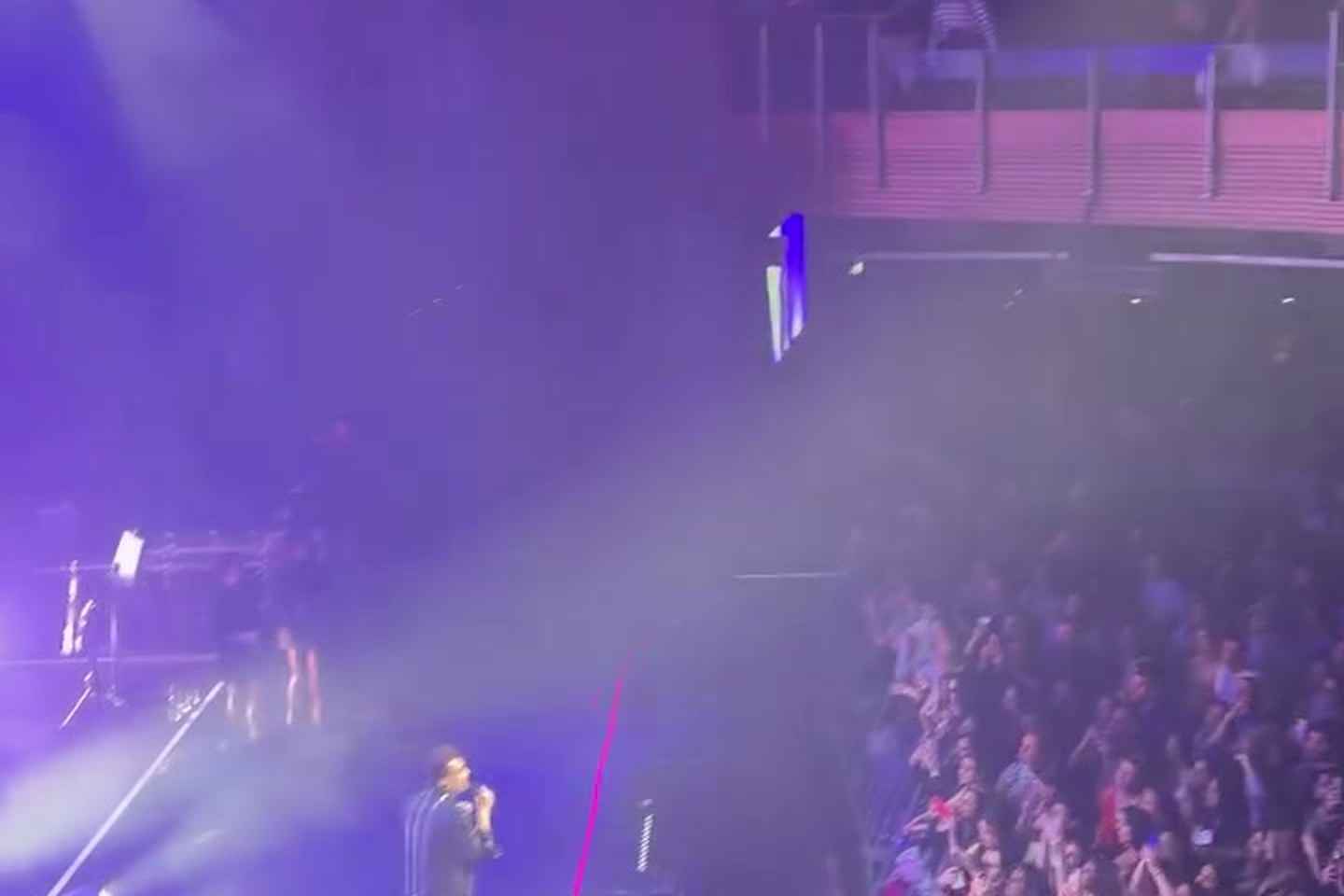 Videographer filming a live concert crowd from front of house