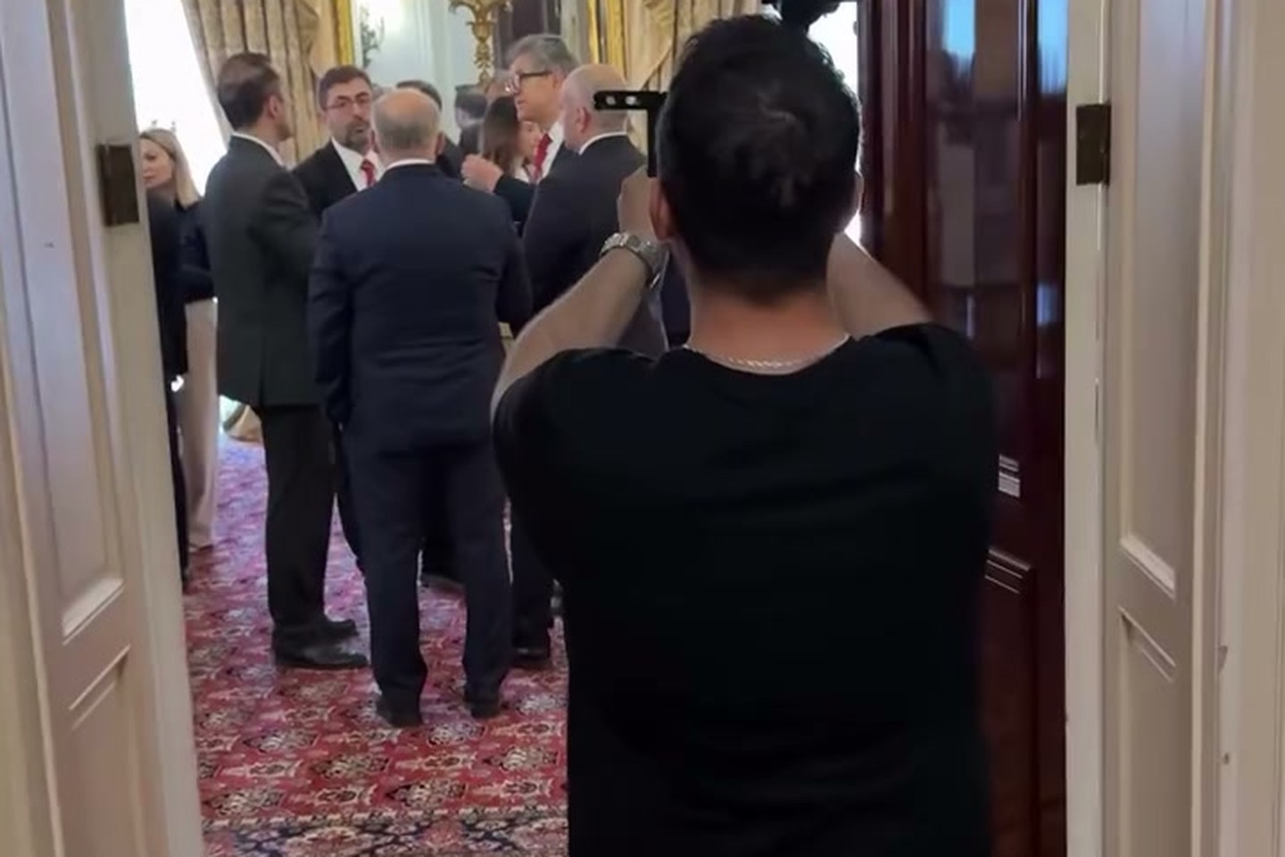 Camera operator filming delegates inside an ornate London venue during a hybrid event